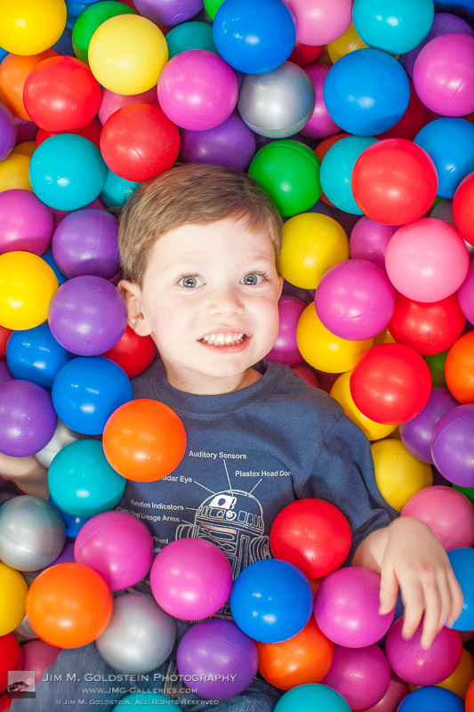 5 year old celebrating a birthday in a colorful plastic ball pit