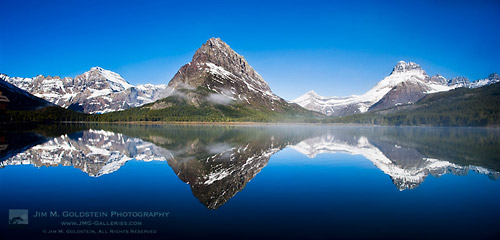 Fog forms over Swiftcurrent Lake and Mount Grinnell at sunrise in Glacier National Park, Montana